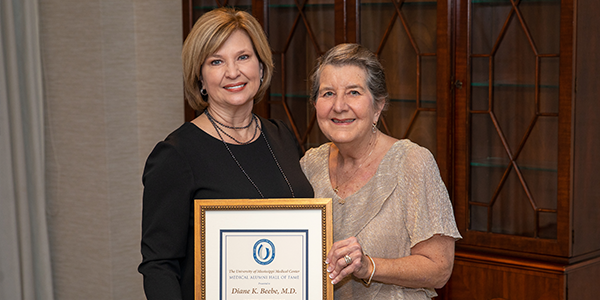 Dr. Diane Beebe accepting her Medical Alumni Chapter Hall of Fame certificate from Dr. LouAnn Woodward